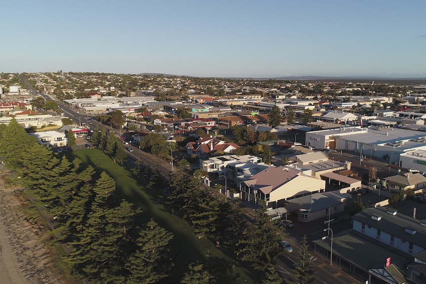 A photo from the sky of a town with houses and gardens. The sky is blue.