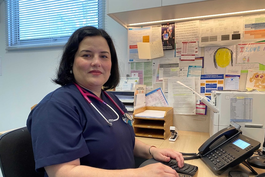 Female doctor with stethoscope around neck sits at computer