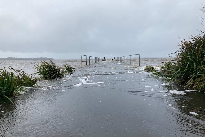 a pathway that heads towards the ocean is overwhelmed with flood waters