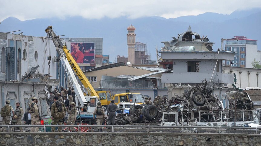 Afghan security personnel inspect the site of the car bomb attack.