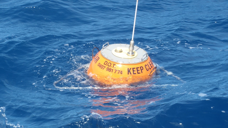 An orange wave buoy rider in the ocean.