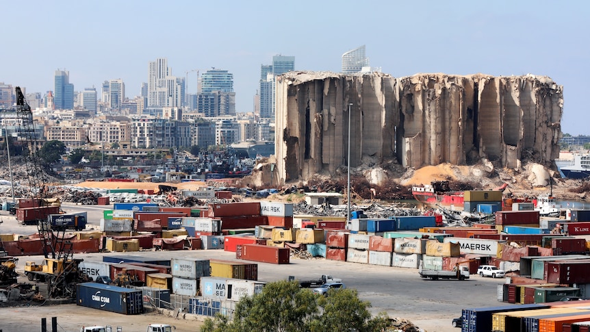 A partially destroyed building at the site of the Beirut port explosion amid multi-coloured containers 