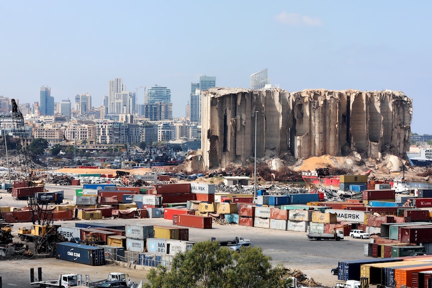 A partially destroyed building at the site of the Beirut port explosion amid multi-coloured containers 