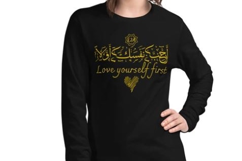 A woman wears a shirt with Arabic writing on it.