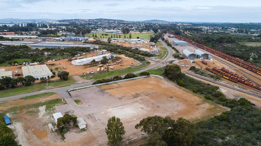 An aerial site view, with the railway and sea in the background