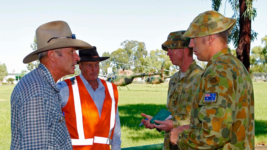 Major Paul Mackenzie (2nd right) and Captain Charles Mansfield (right) discuss the flood damage recovery plan in Mitchell