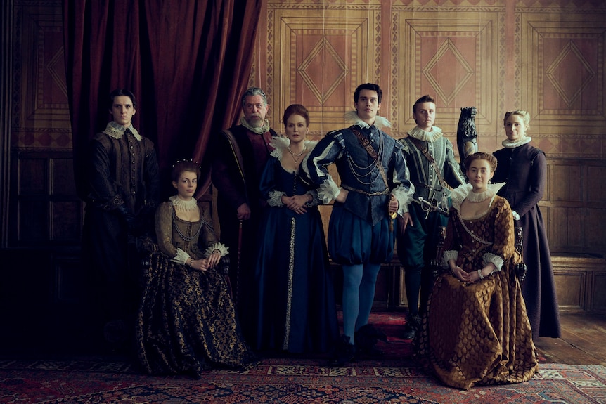 The characters in Mary and George sit for a portrait, with George standing proudly with his hands on his hips