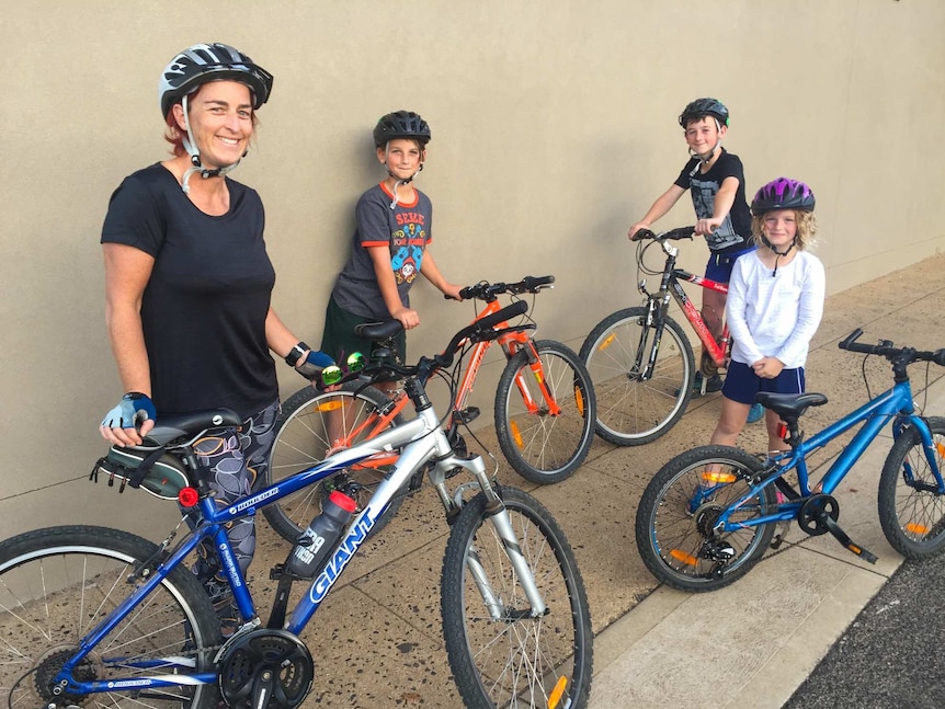 Woman and three children with bicycles.