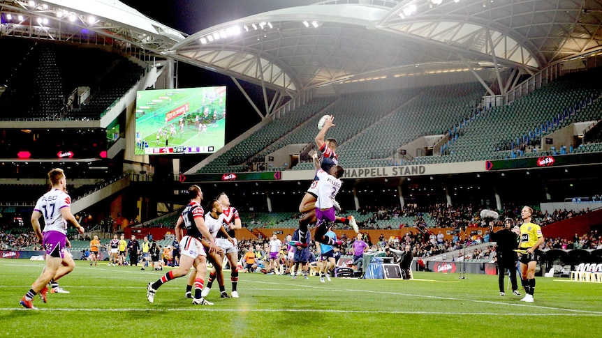 Two NRL players leap high for the ball at Adelaide Oval.