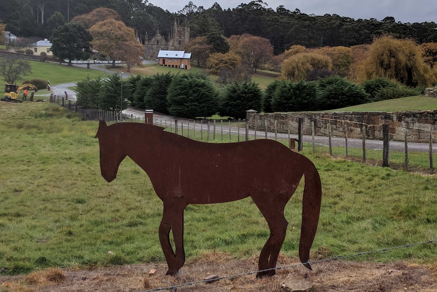 A horse sculpture standing on a hill overlooking the buildings at Port Arthur.