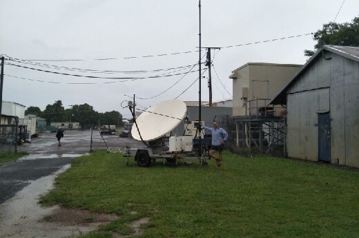 A Telstra technician stands next to a portable satellite in Daly River.