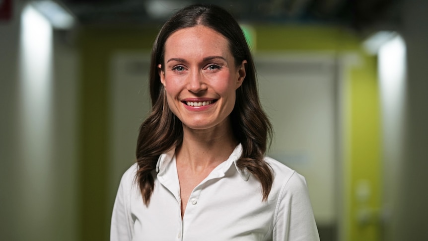 Woman with brown hair wearing a white shirt, smiling. 