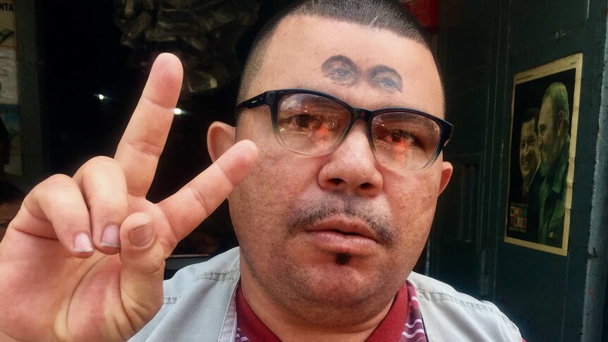 A Hugo Chavez supporter with the late Venezuelan leader's eyes tattooed on his forehead poses for a photograph.