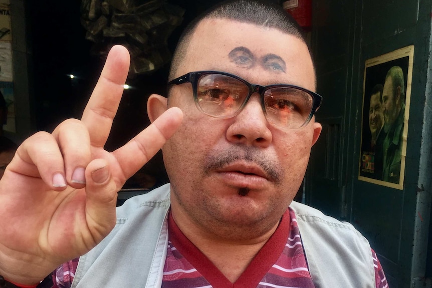 A Hugo Chavez supporter with the late Venezuelan leader's eyes tattooed on his forehead poses for a photograph.