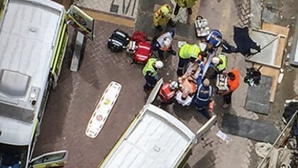Ambulance officers assess men injured during a crane collapse.