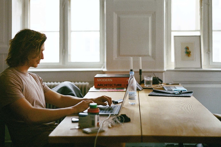 A man at his kitchen table working on a laptop computer