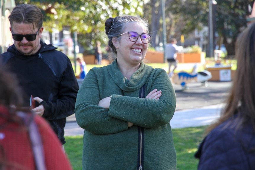 A woman wearing green laughs in the park 