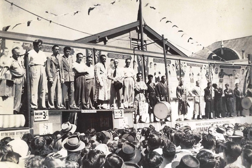 A group of men stand on stage as part of the Jimmy Sharman Boxing Troupe.