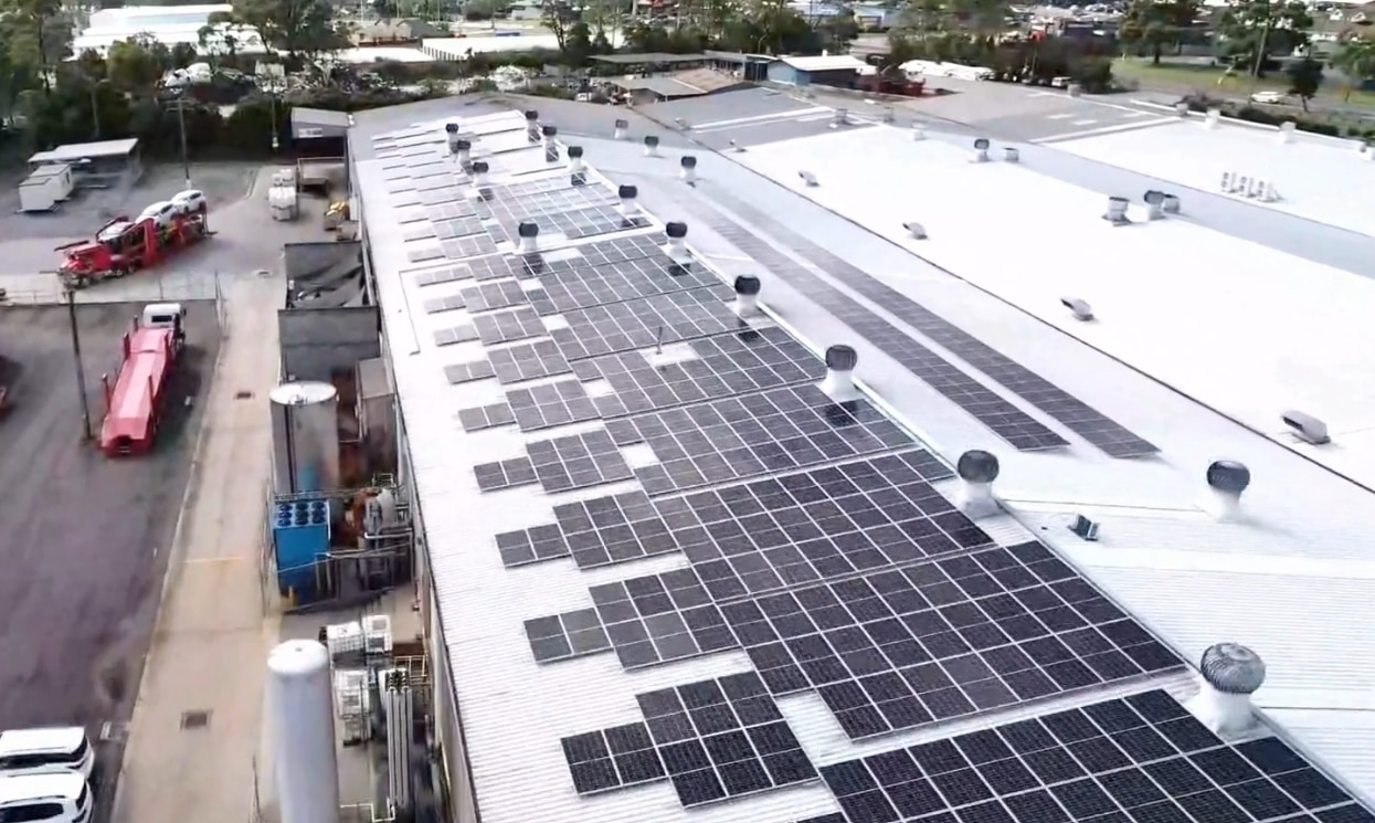 An aerial view of a factory roof covered in solar panels.