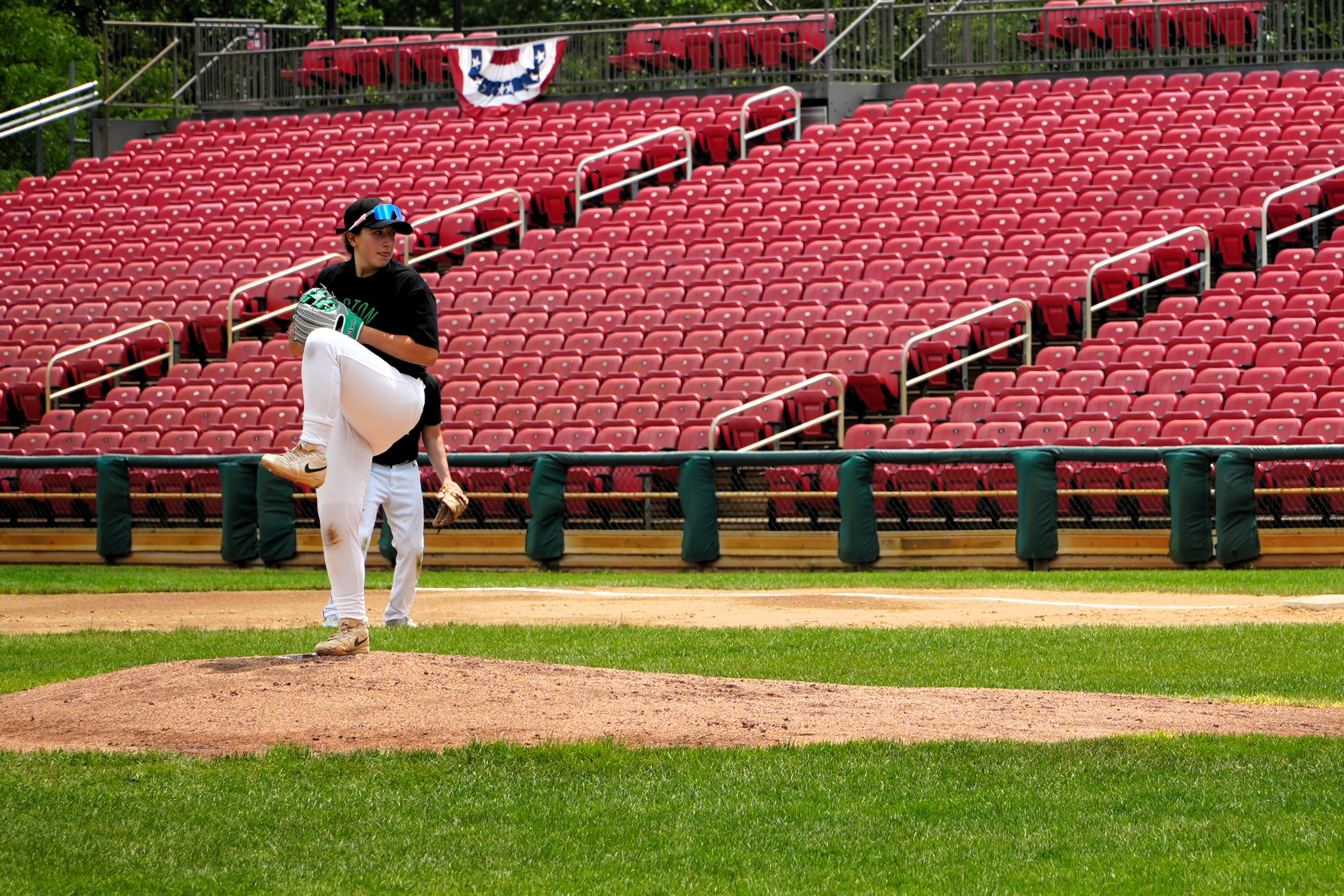 A female baseball pitcher is on the mound preparing to throw a pitch