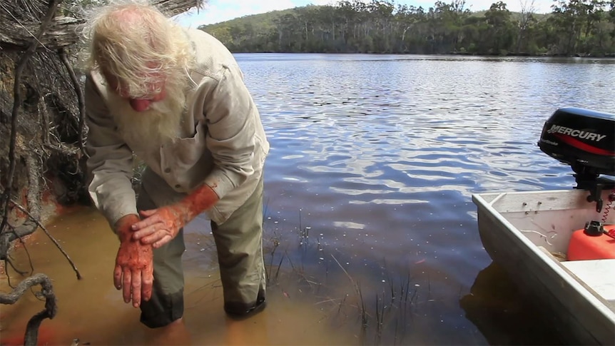 Bruce Pascoe washes his hands in a water source