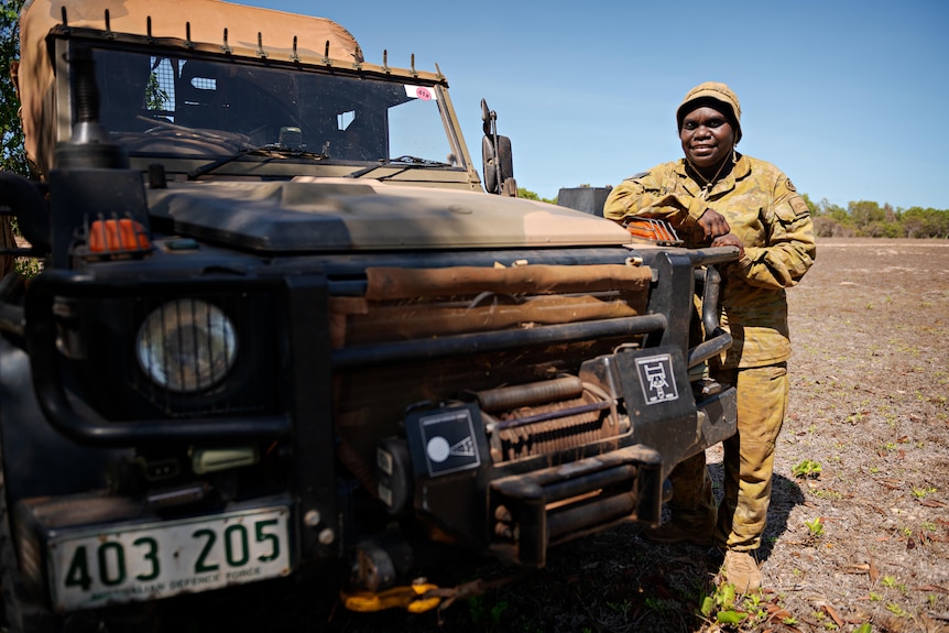 an aboriginal woman wearing army uniform standing next to a vehicle