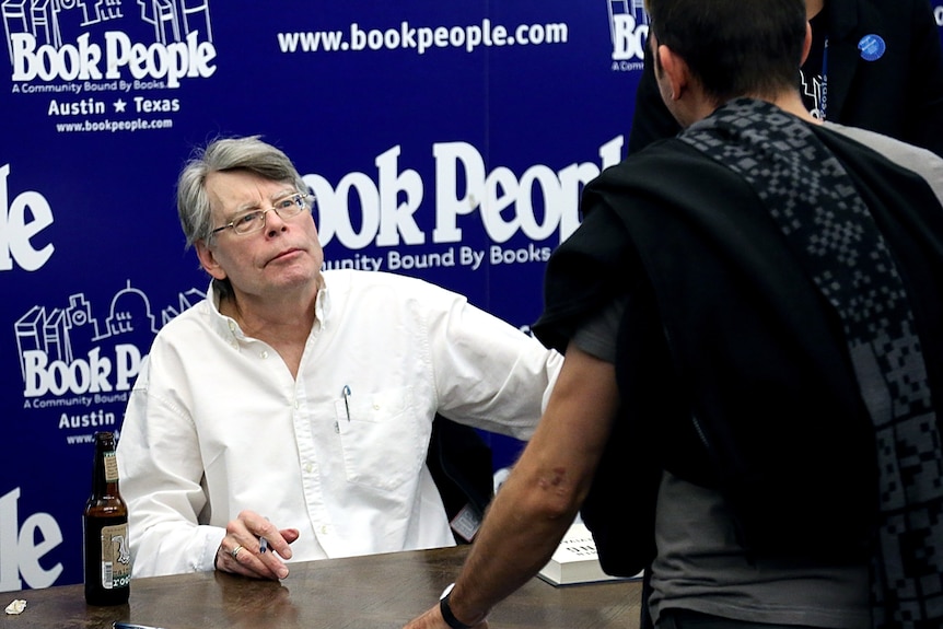 Silver haired man signing books