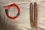 Two homemade explosives and a thick red wire on a white bedsheet.