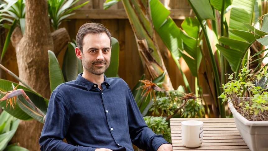 Graham Panther sitting at a table in his backyard with a cup of tea, contemplating how to make plans for another pandemic year.