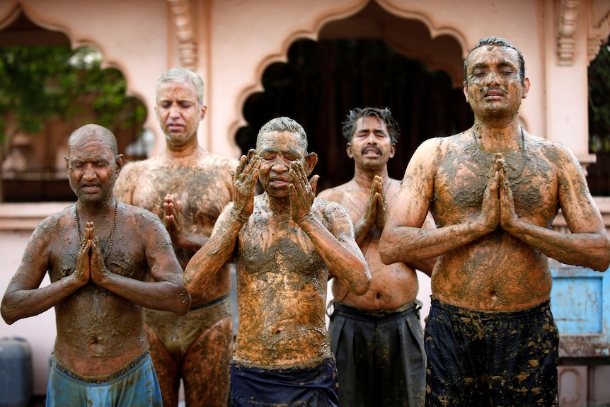 Hindu men pray for protection from COVID after applying cow dung on their bodies.