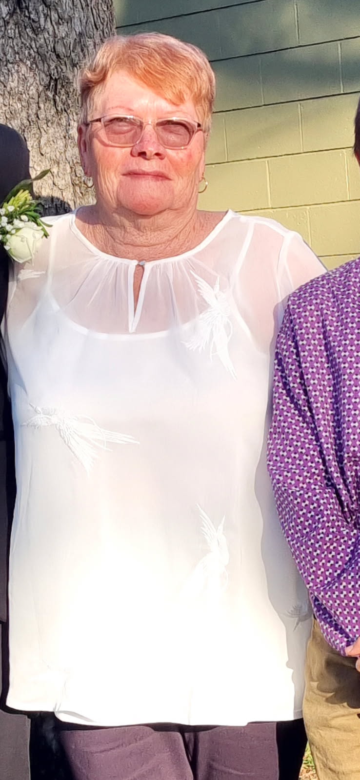 Una mujer mayor con pelo corto, gafas y aros.