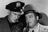Bud Abbott and Lou Costello are dressed in police hats as they pose for a publicity photograph.