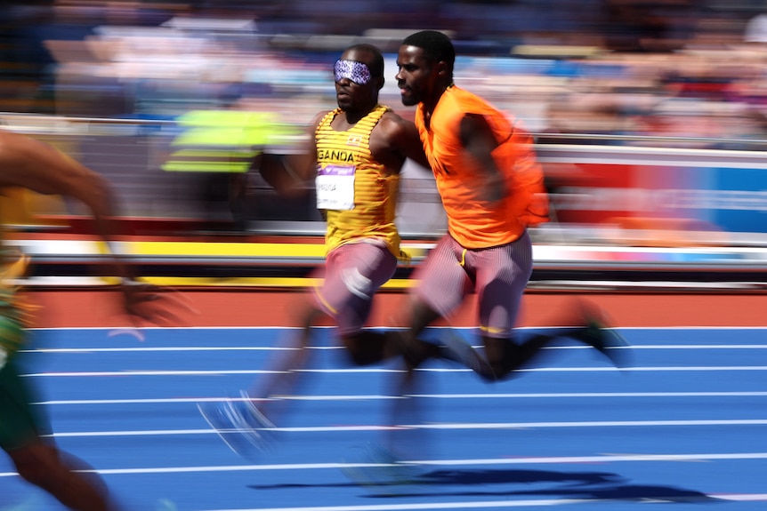 Two men, one wearing an eye shield, during a running race