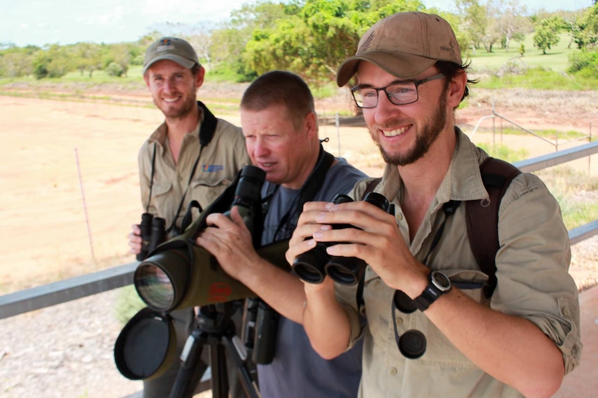 Three men with binoculars and a telescope.