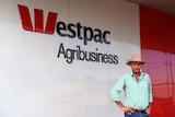 Man in cowboy hat stands outside westpac bank branch