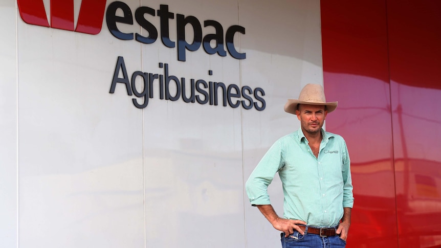 Man in cowboy hat stands outside westpac bank branch