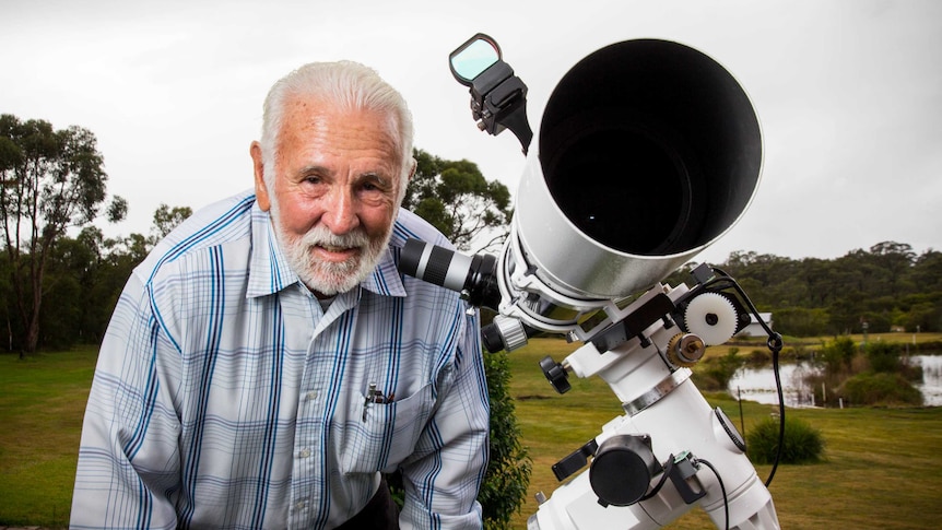 Col Maybury leans towards the eyepiece of his telescope.
