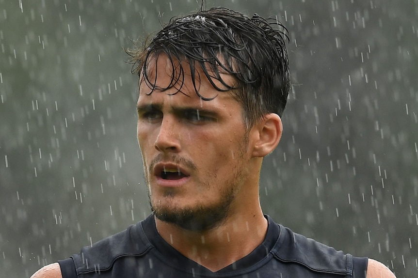 Melbourne Demons player Harley Balic stands in the rain at AFL training.