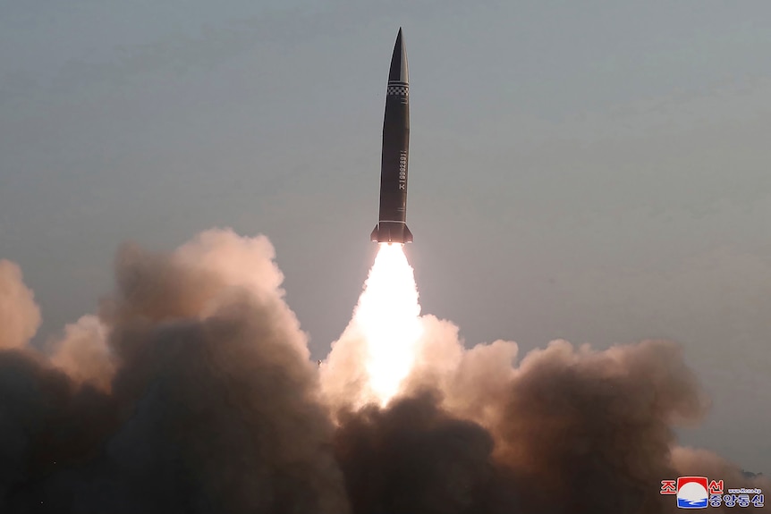 A rocket is seen firing into the air leaving a cloud of smoke below it.