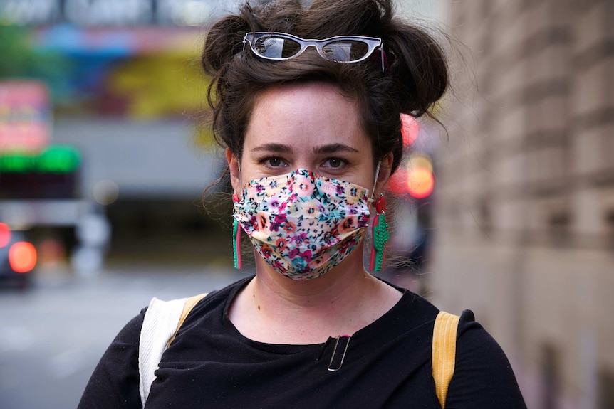 A woman is walking down a street wearing a colourful face mask.