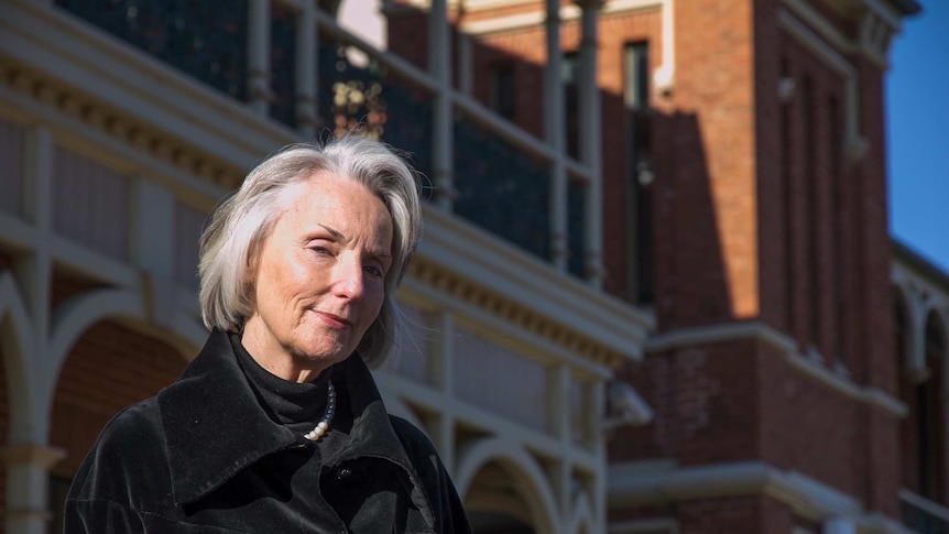 A woman standing in front of a historic hospital building