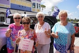 Four older women with their thumbs up holding 'women for Trump signs'