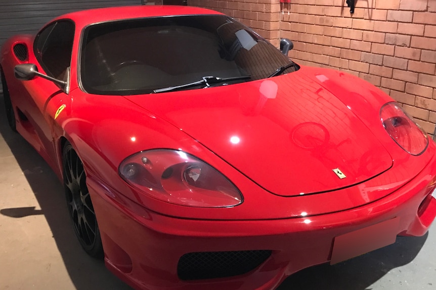 A red Ferrari in a small brick garage.
