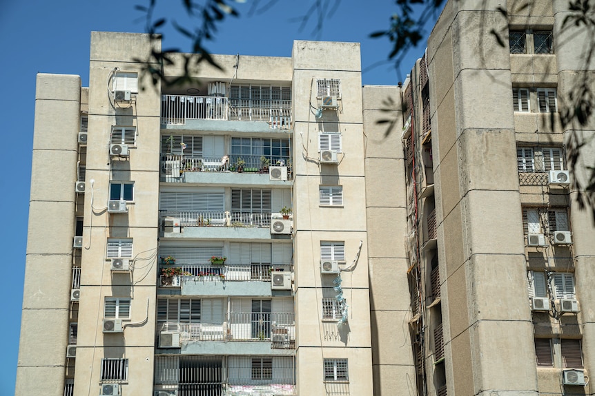 Air conditioners line a building of apartment blocks.