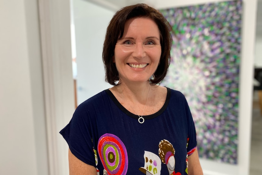 a portrait photograph of woman looking at the camera and smiling in her home office