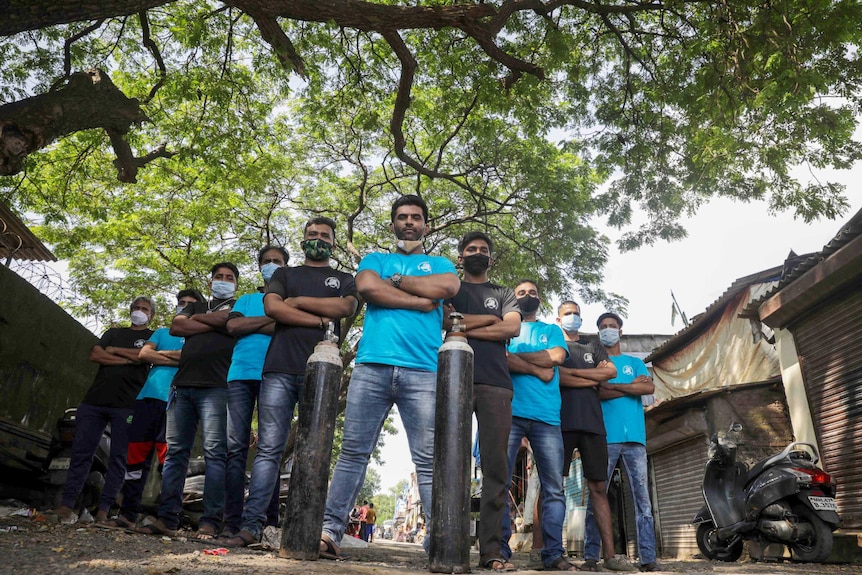 A group of men in face masks with their arms crossed