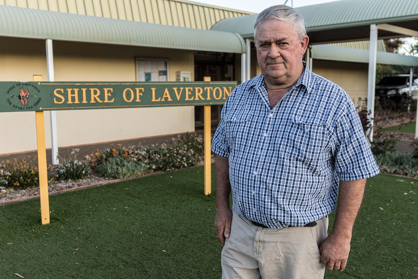 A man in a collared shirt standing in front of a council administration building.