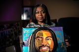 A woman holds a painting of her late son