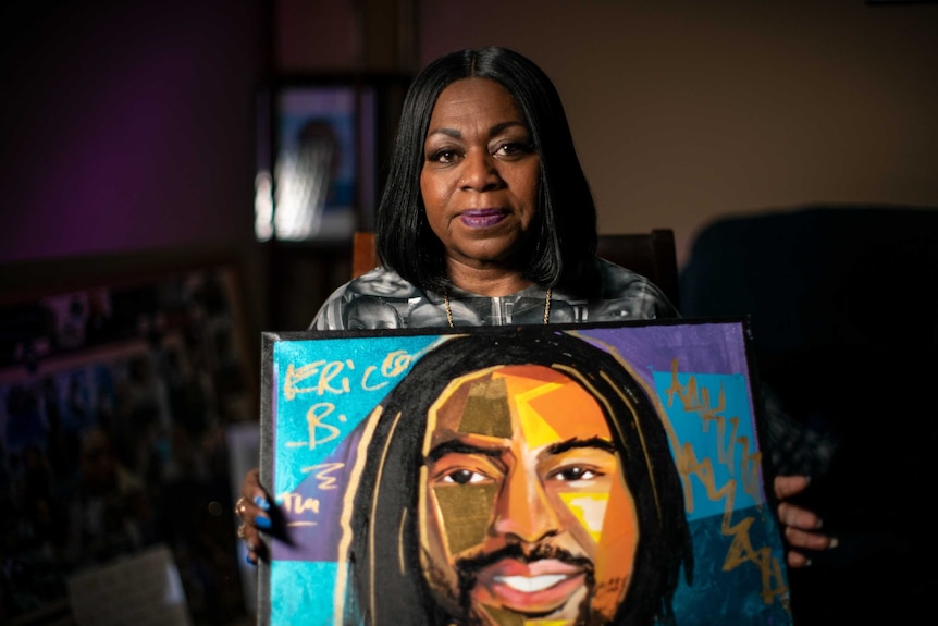 A woman holds a painting of her late son