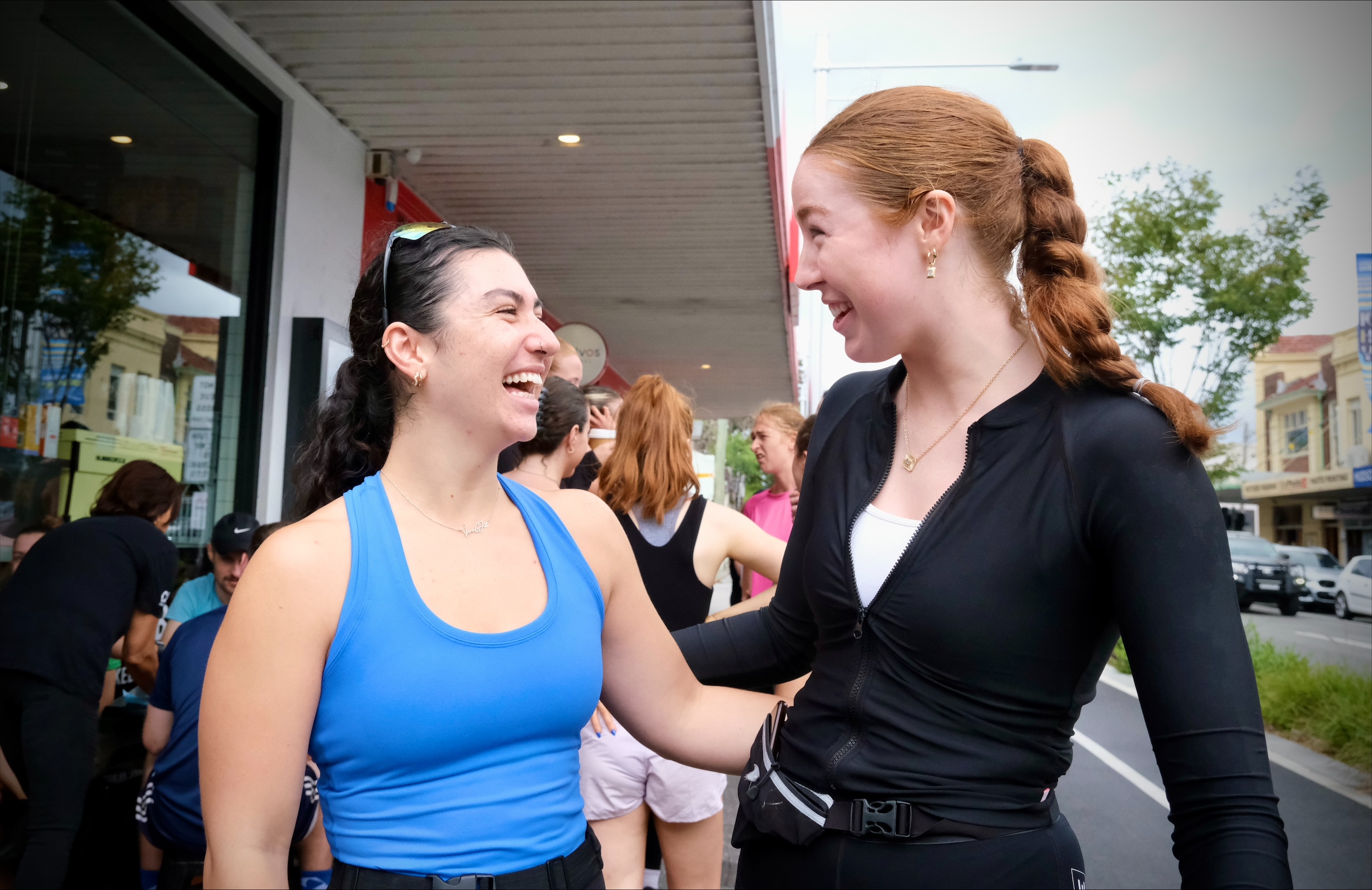 Tara Gallagher, left, organiser of the Croissant Run Club smiling and talking to a fellow runner outside a Sydney cafe